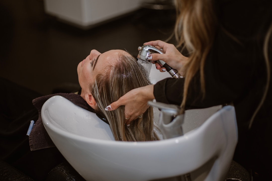 Close-up of a hairstylist cutting straight brown hair with scissors and a comb.