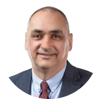 Portrait of a middle-aged man wearing a navy blazer, light blue shirt, and maroon tie, smiling at the camera.