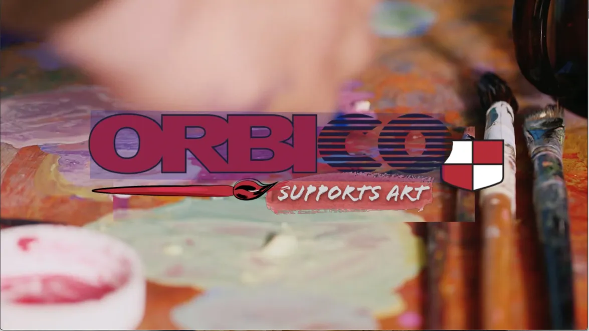 Close-up of paintbrushes and paint palette with mixed colors on a wooden surface.